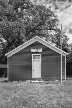 Historic rural schoolhouse with a white doorway and American flag.