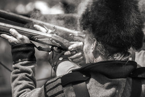 Close view of a militia reenactor aiming a smoking musket.
