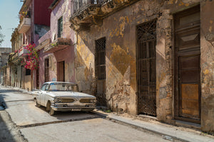 Sunlit Havana street with a vintage car and peeling plaster walls