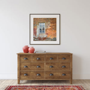 Weathered orange plaster and exposed brick around an Italian window