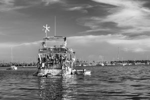 Old yacht with fenders and a small dinghy in Key West harbour