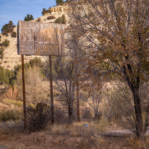Faded RV Tours roadside sign surrounded by dry trees in Utah