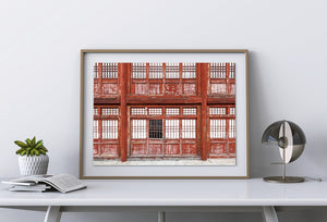Puertas rojas desgastadas debajo de patrones repetidos de ventanas en la Gran Muralla China