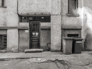 Scena di strada rumena in bianco e nero con una vecchia porta e intonaco usurato