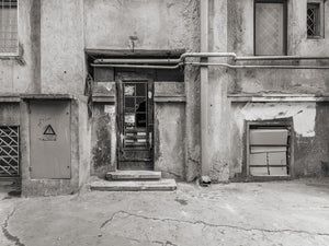Old Romanian building facade with a damaged door and exposed pipework