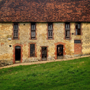 Old French stone facade with red brick window surrounds and tiled roof