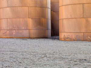 Curved rusted tanks with rows of rivets on Antarctic gravel