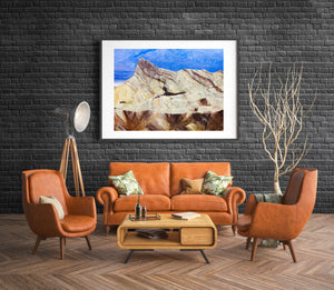 Warm yellow badlands striped with dark brown seams below blue mountains